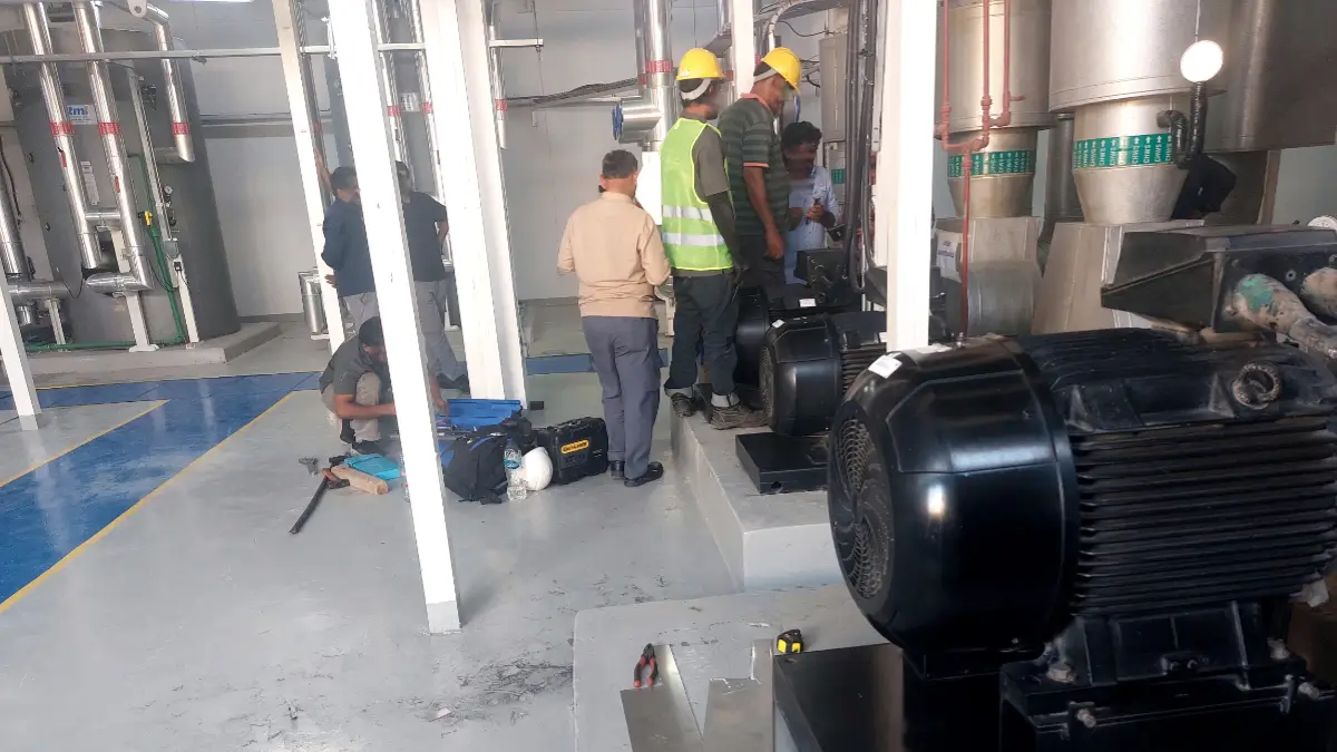 Technicians inspecting a hospital pump motor during laser alignment and maintenance